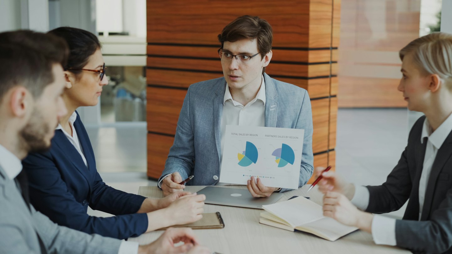 Equipo diverso de negocios colaborando alrededor de una mesa durante una reunión.